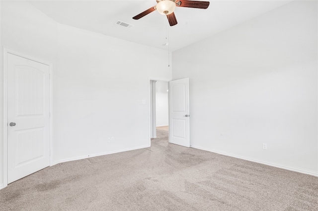 carpeted empty room with ceiling fan and a towering ceiling