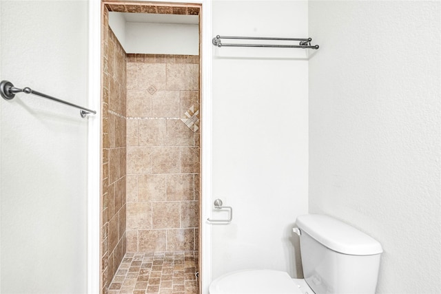 bathroom with toilet and a tile shower