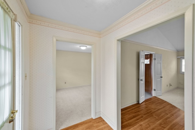 hall featuring light wood-type flooring, lofted ceiling, a wealth of natural light, and crown molding