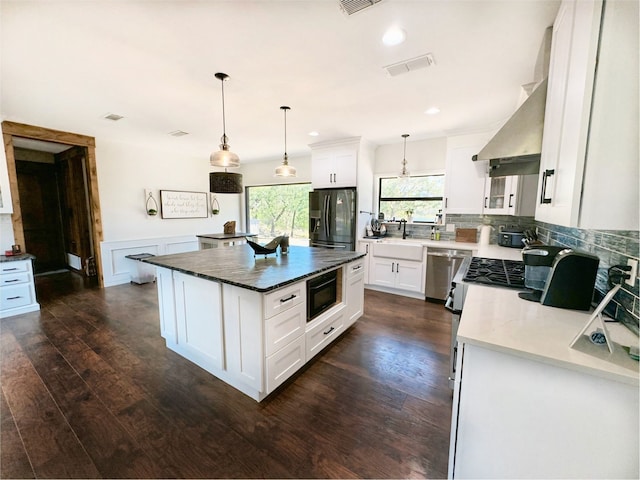 kitchen with decorative light fixtures, stainless steel appliances, white cabinetry, dark wood-type flooring, and a kitchen island