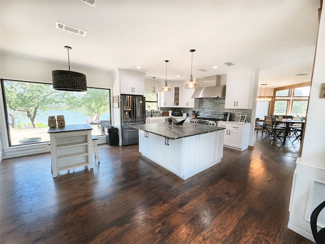 kitchen featuring dark hardwood / wood-style floors, a center island, stainless steel appliances, white cabinetry, and wall chimney range hood