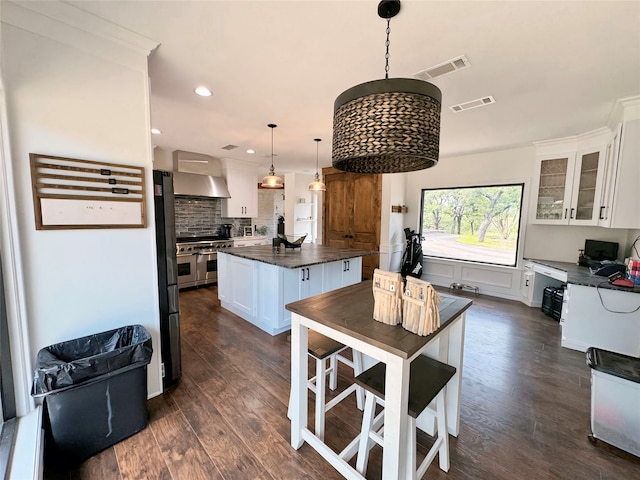 kitchen featuring white cabinetry, a kitchen island, hanging light fixtures, dark hardwood / wood-style floors, and appliances with stainless steel finishes