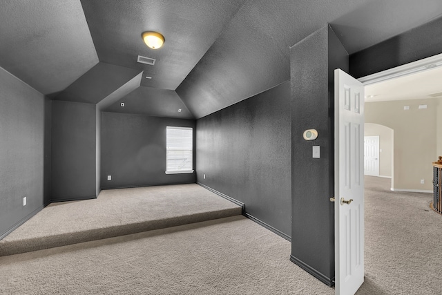 interior space featuring lofted ceiling, a textured ceiling, and light colored carpet