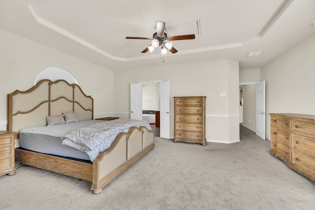 bedroom featuring a tray ceiling, ceiling fan, carpet floors, and ensuite bathroom