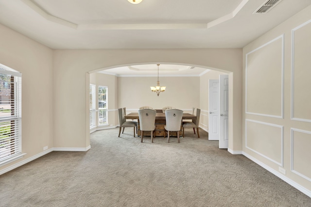 dining space with ornamental molding, a raised ceiling, a chandelier, and carpet