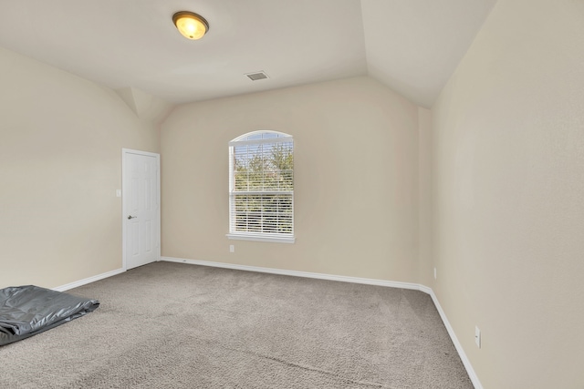 carpeted empty room with lofted ceiling