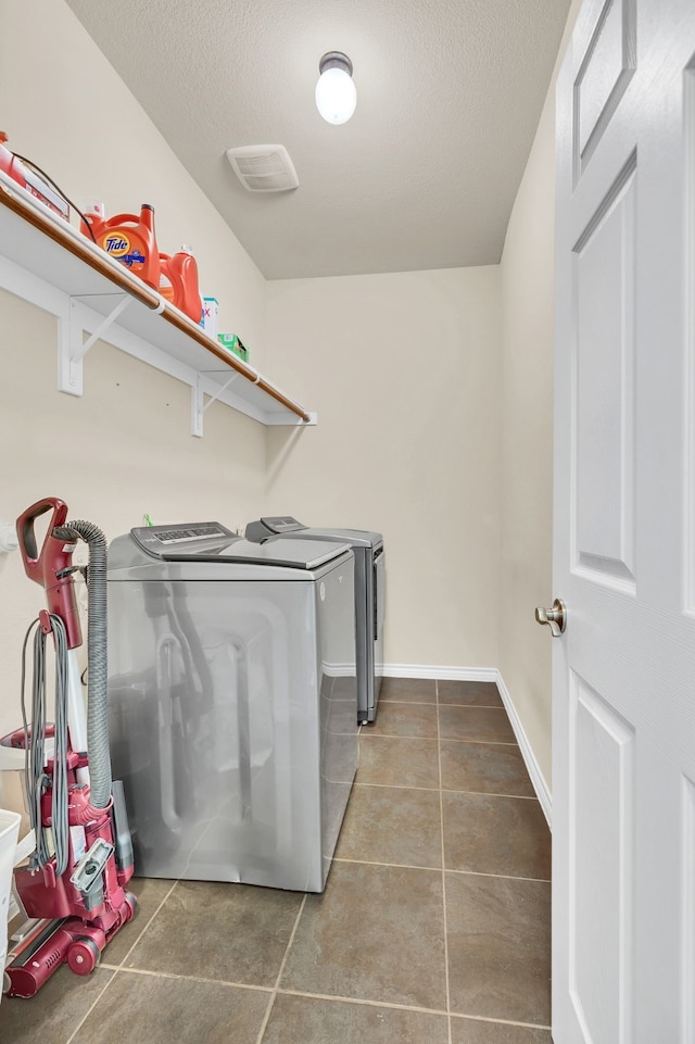 clothes washing area featuring a textured ceiling, washing machine and dryer, and tile patterned floors