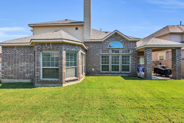 rear view of property featuring a lawn and a patio