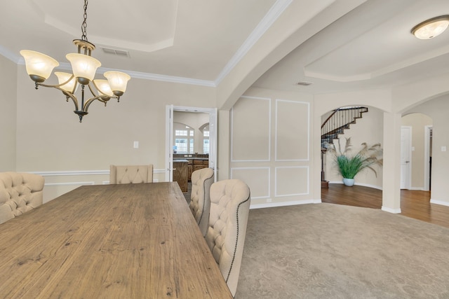 unfurnished dining area featuring carpet flooring, ornamental molding, a raised ceiling, and a chandelier