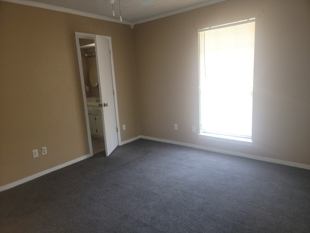 unfurnished room with ornamental molding, a textured ceiling, and dark carpet