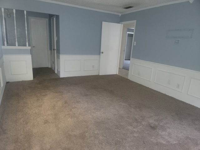 carpeted spare room with a textured ceiling and crown molding