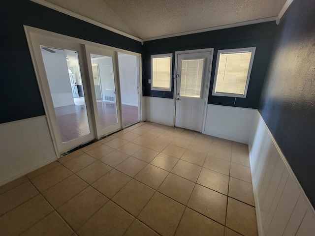 unfurnished room with crown molding, a textured ceiling, and light tile patterned floors