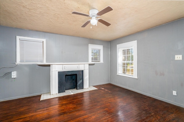 unfurnished living room with a textured ceiling, dark wood-type flooring, and ceiling fan