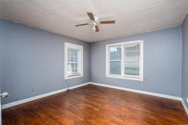 empty room featuring dark wood-type flooring, a textured ceiling, a healthy amount of sunlight, and ceiling fan