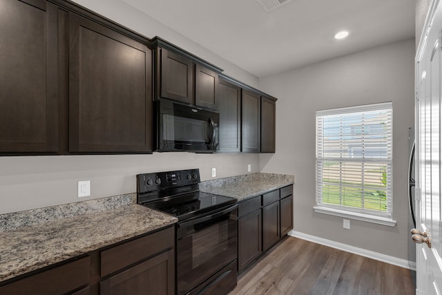 kitchen featuring black appliances, dark brown cabinetry, light stone countertops, and light hardwood / wood-style floors