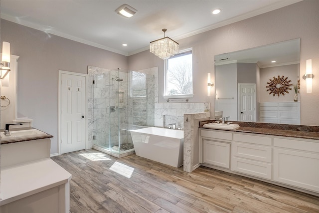 bathroom with crown molding, hardwood / wood-style flooring, vanity, and separate shower and tub