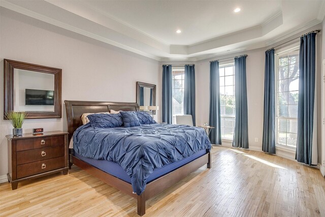 bedroom featuring a tray ceiling, light hardwood / wood-style floors, and crown molding