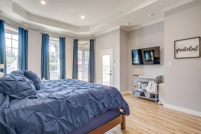 bedroom featuring light hardwood / wood-style flooring, a raised ceiling, and crown molding