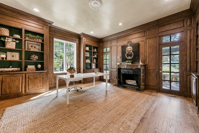 office with built in features, crown molding, wood walls, and light hardwood / wood-style floors