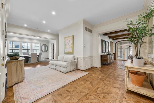 living room with light parquet floors, crown molding, beamed ceiling, and french doors