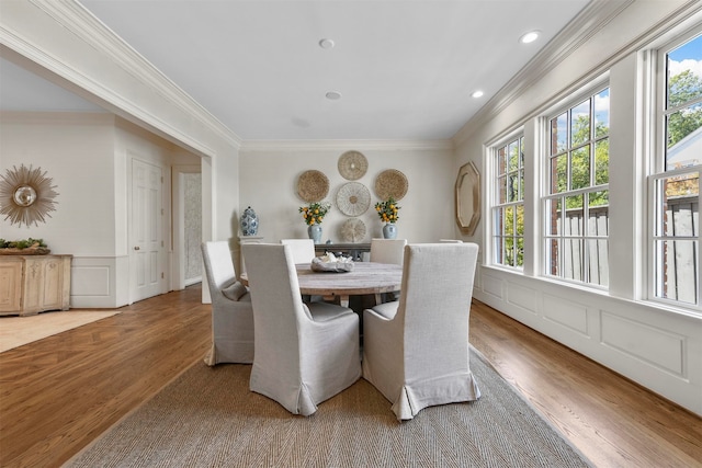 dining space with crown molding and light hardwood / wood-style floors