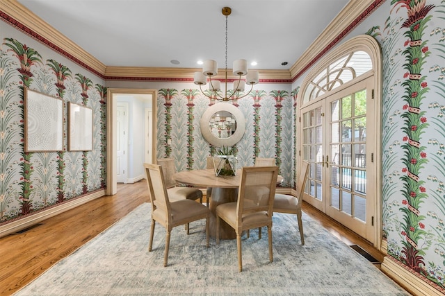 dining area featuring ornamental molding, french doors, an inviting chandelier, and light hardwood / wood-style floors