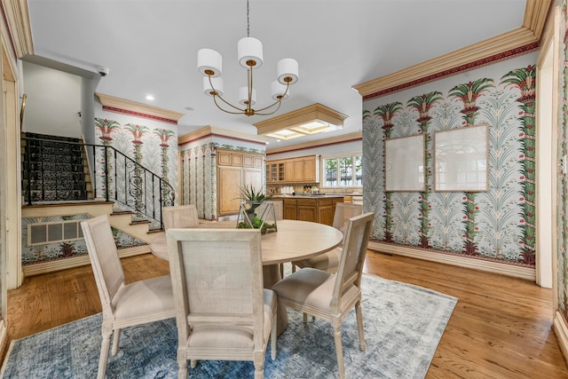 dining space featuring light wood-type flooring, a chandelier, and ornamental molding