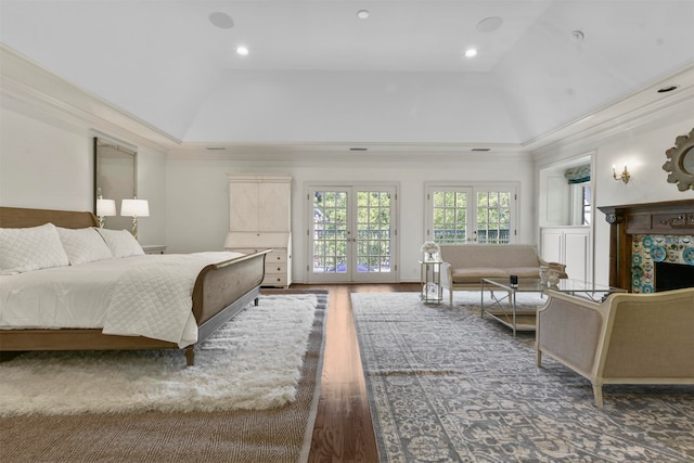 bedroom featuring a tiled fireplace, hardwood / wood-style floors, french doors, crown molding, and access to exterior