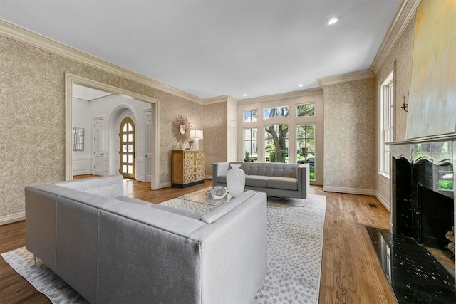 living room with a high end fireplace, ornamental molding, and hardwood / wood-style flooring