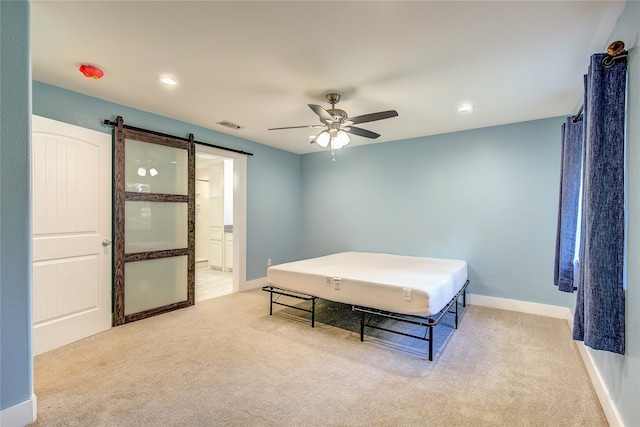 carpeted bedroom featuring a barn door and ceiling fan