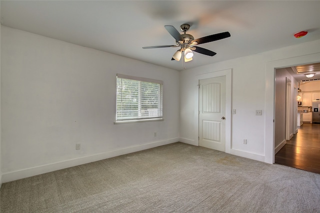 unfurnished bedroom featuring stainless steel refrigerator with ice dispenser, carpet floors, and ceiling fan