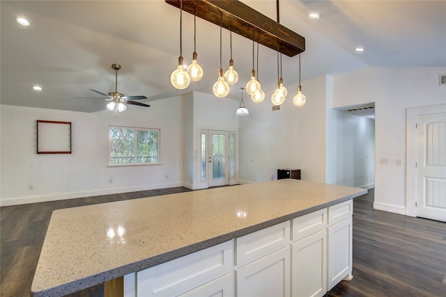 kitchen featuring dark hardwood / wood-style flooring, ceiling fan, vaulted ceiling, white cabinets, and light stone counters