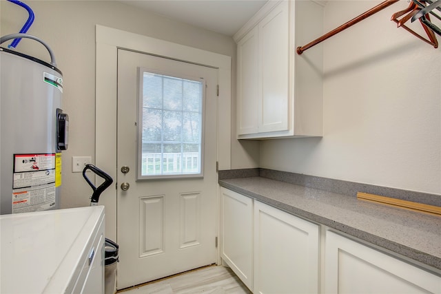 laundry room featuring water heater and cabinets