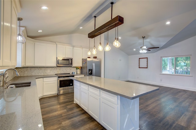 kitchen featuring appliances with stainless steel finishes, vaulted ceiling, sink, dark wood-type flooring, and a center island