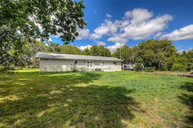 back of property with a deck and a lawn