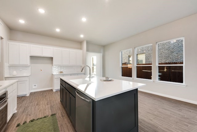 kitchen with a center island with sink, white cabinets, stainless steel dishwasher, and sink