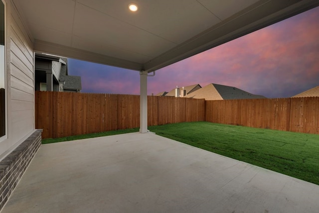 patio terrace at dusk featuring a yard