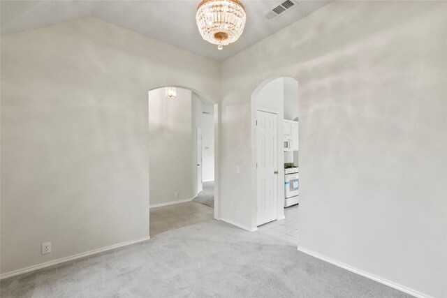 carpeted empty room with vaulted ceiling and a chandelier