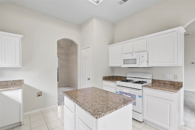 kitchen featuring light tile patterned floors, white appliances, a kitchen island, and white cabinetry