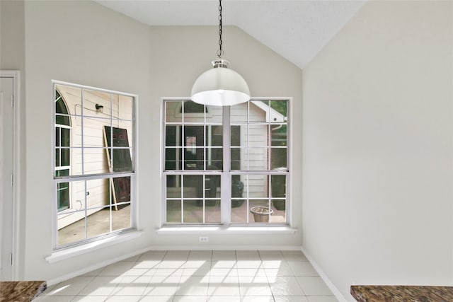 unfurnished dining area featuring lofted ceiling, plenty of natural light, and tile patterned floors