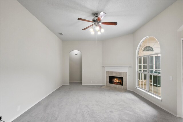 unfurnished living room with a fireplace, a textured ceiling, ceiling fan, and carpet