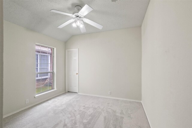 carpeted empty room with lofted ceiling, ceiling fan, and a textured ceiling