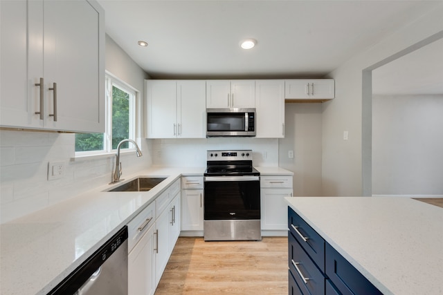 kitchen featuring blue cabinetry, white cabinets, stainless steel appliances, and sink