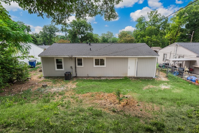 back of house with central air condition unit and a yard