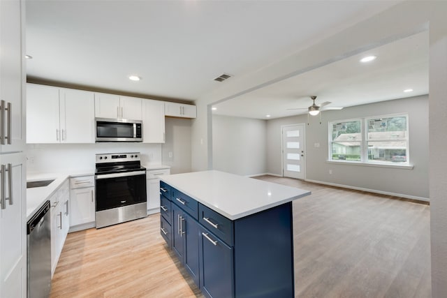 kitchen with white cabinetry, a kitchen island, blue cabinetry, stainless steel appliances, and ceiling fan