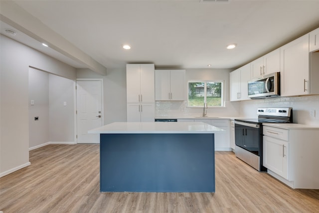 kitchen featuring white cabinetry, stainless steel appliances, a center island, light hardwood / wood-style flooring, and sink