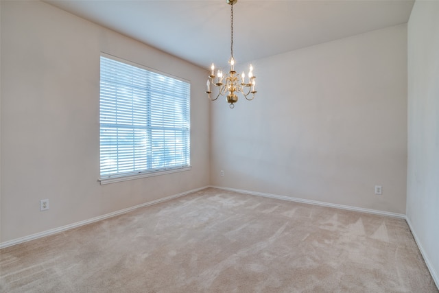 spare room with a notable chandelier and light colored carpet