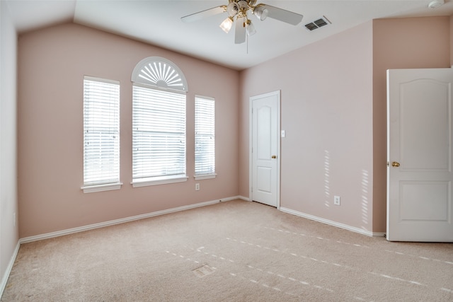 spare room featuring light carpet, vaulted ceiling, and plenty of natural light