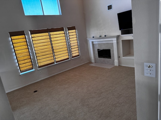 unfurnished living room featuring carpet flooring and a tiled fireplace