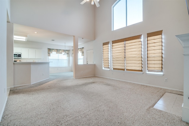 spare room with a high ceiling, light colored carpet, and ceiling fan